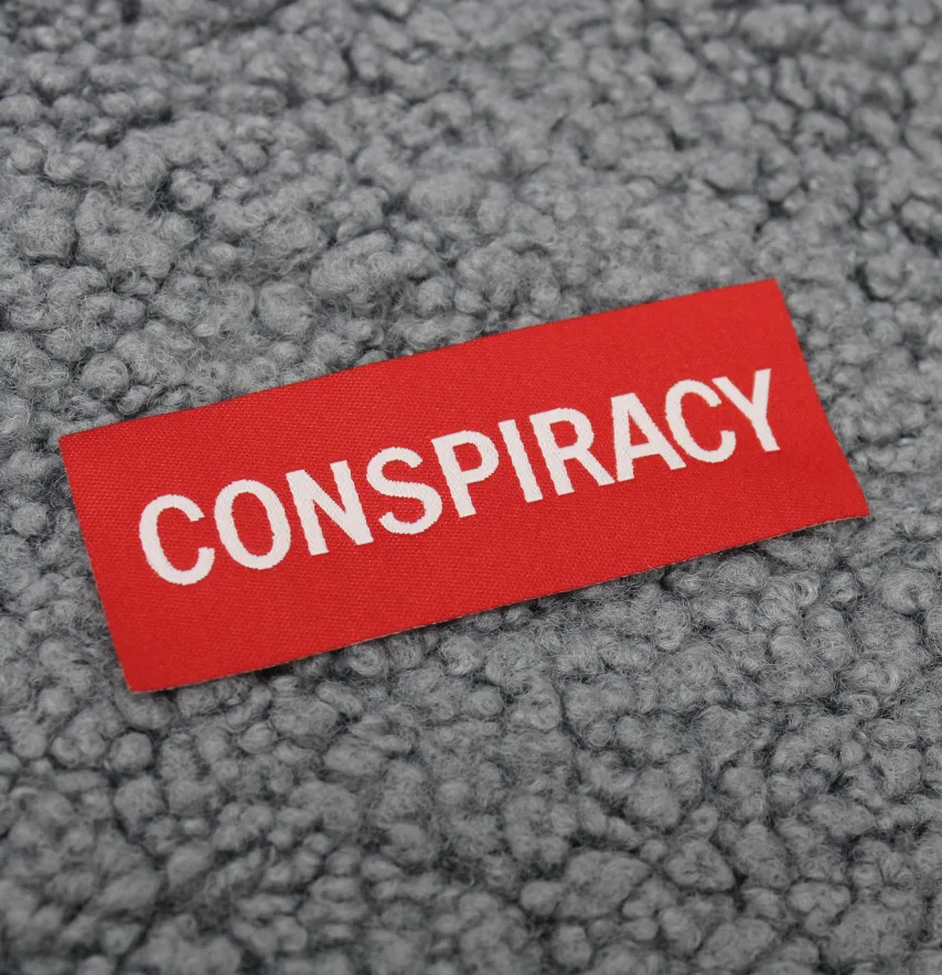 Нашивка жаккардова "CONSPIRACY" 80*30 мм червоного кольору на флізеліновій основі-0