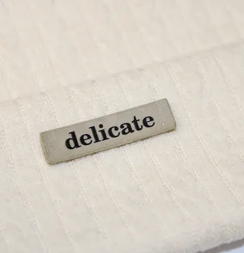 Нашивка "Delicate" 40*10 мм бежевого цвета с черной надписью.